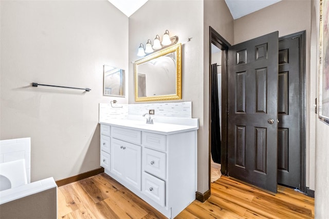 bathroom with hardwood / wood-style flooring, vanity, and tasteful backsplash