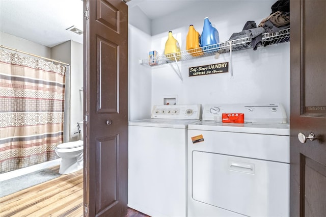 laundry area with hardwood / wood-style flooring and washing machine and clothes dryer