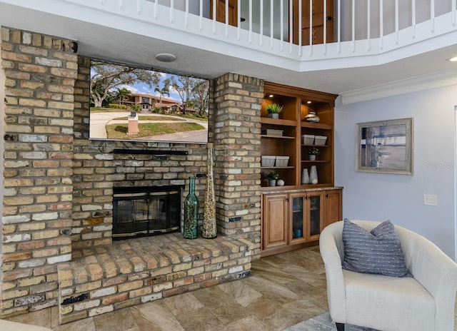 living room with crown molding, a brick fireplace, and a towering ceiling