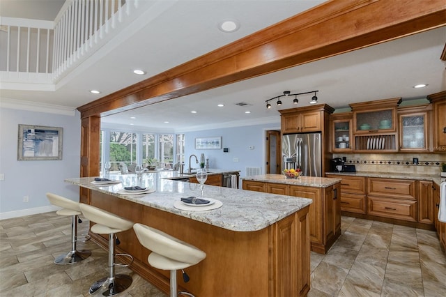 kitchen featuring stainless steel refrigerator with ice dispenser, ornamental molding, a large island, and a breakfast bar