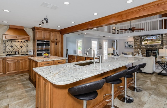 kitchen with a large island with sink, light stone countertops, and a kitchen breakfast bar