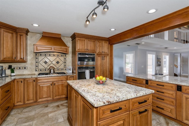 kitchen with light stone counters, custom range hood, and appliances with stainless steel finishes