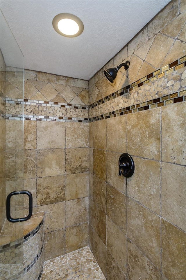 details featuring a shower with door and a textured ceiling