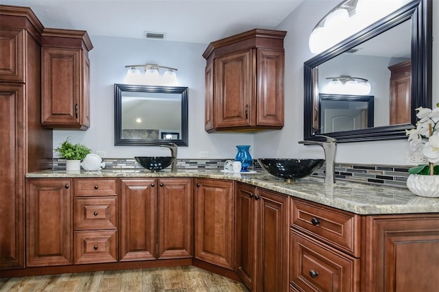 kitchen with light hardwood / wood-style floors, light stone countertops, and sink