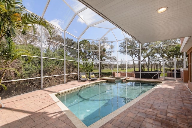 view of pool with an in ground hot tub, glass enclosure, and a patio