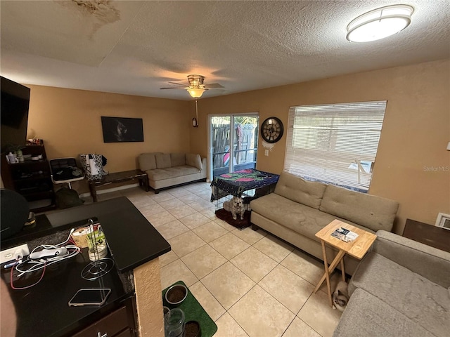 living room with light tile patterned flooring, ceiling fan, and a textured ceiling