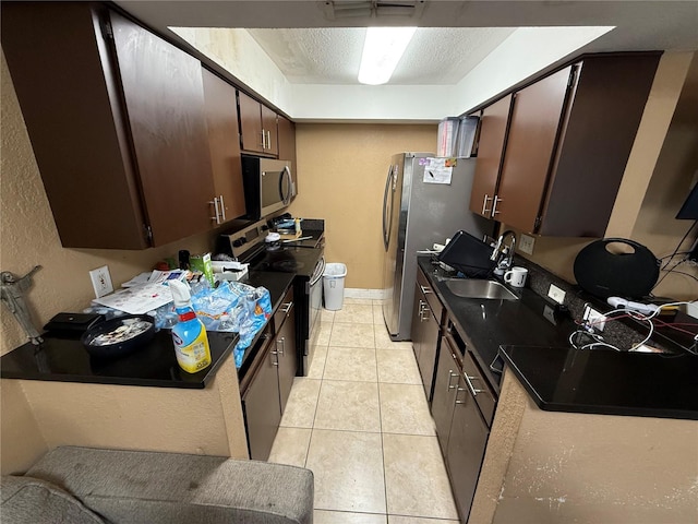 kitchen with dark brown cabinetry, sink, a textured ceiling, light tile patterned floors, and stainless steel appliances