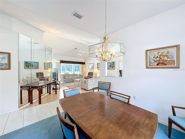 tiled dining space featuring lofted ceiling and ceiling fan with notable chandelier