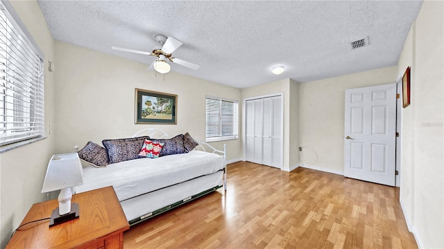 bedroom featuring ceiling fan, light hardwood / wood-style floors, and a textured ceiling