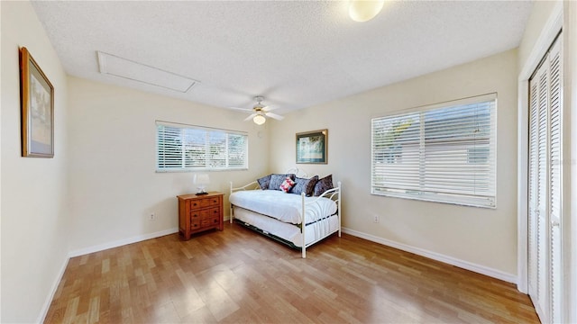 bedroom featuring ceiling fan, hardwood / wood-style floors, and a textured ceiling