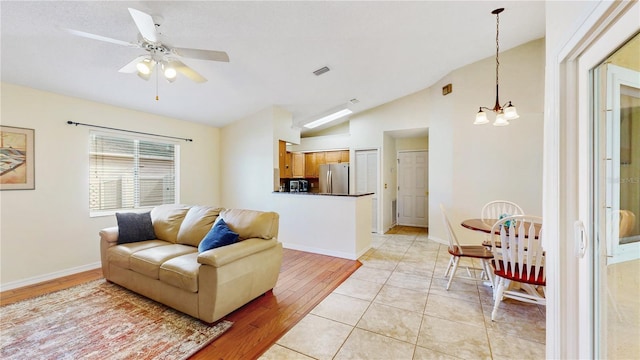 living room with lofted ceiling, ceiling fan with notable chandelier, and light hardwood / wood-style flooring