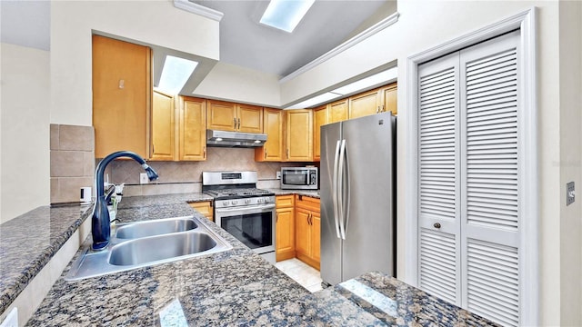 kitchen with tasteful backsplash, appliances with stainless steel finishes, sink, and dark stone counters