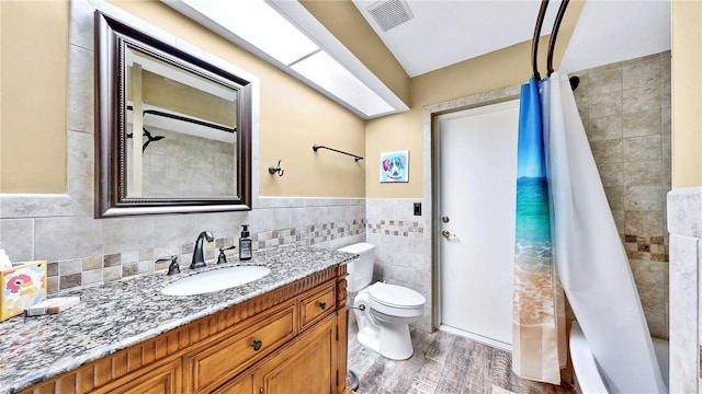 bathroom with tile walls, vanity, curtained shower, and toilet