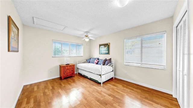 bedroom with ceiling fan, light hardwood / wood-style flooring, and a textured ceiling