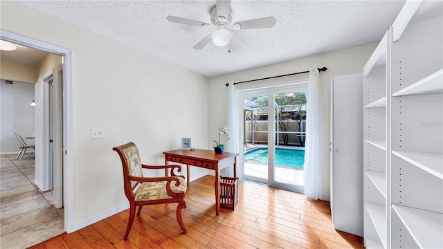 office space with ceiling fan, a textured ceiling, and light wood-type flooring