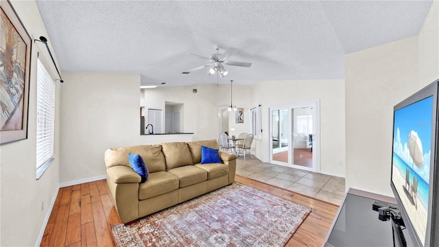 living room featuring lofted ceiling, light hardwood / wood-style flooring, ceiling fan, and plenty of natural light