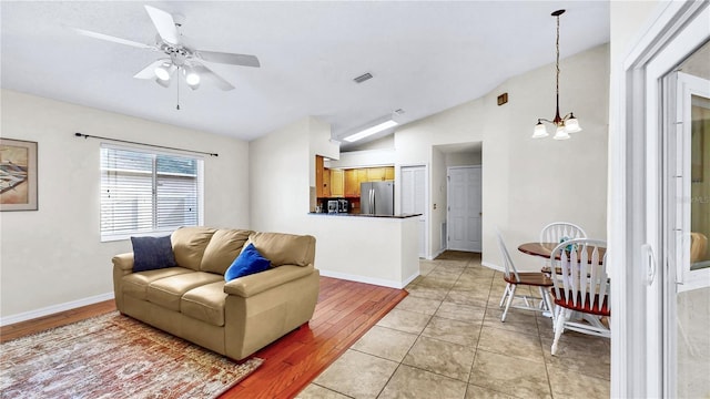 tiled living room with lofted ceiling and ceiling fan with notable chandelier