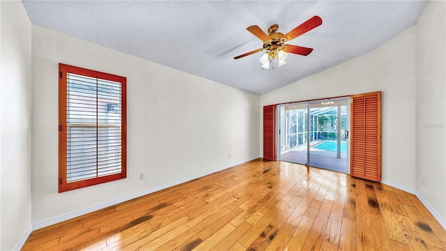 spare room featuring ceiling fan, lofted ceiling, light hardwood / wood-style floors, and a textured ceiling