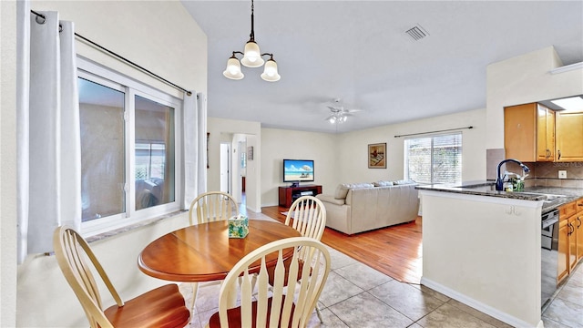 dining room featuring ceiling fan with notable chandelier, sink, and light tile patterned floors