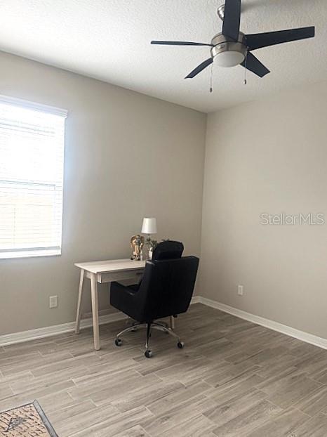 office area with ceiling fan, light hardwood / wood-style floors, and a textured ceiling