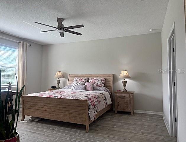 bedroom featuring hardwood / wood-style floors, ceiling fan, and a textured ceiling