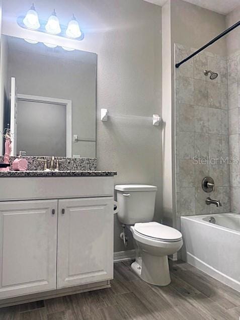 full bathroom with toilet, hardwood / wood-style flooring, vanity, and tiled shower / bath