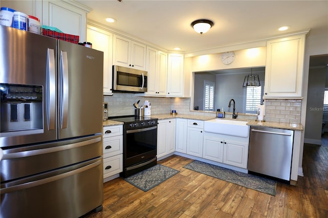 kitchen with sink, white cabinetry, hanging light fixtures, stainless steel appliances, and dark hardwood / wood-style flooring