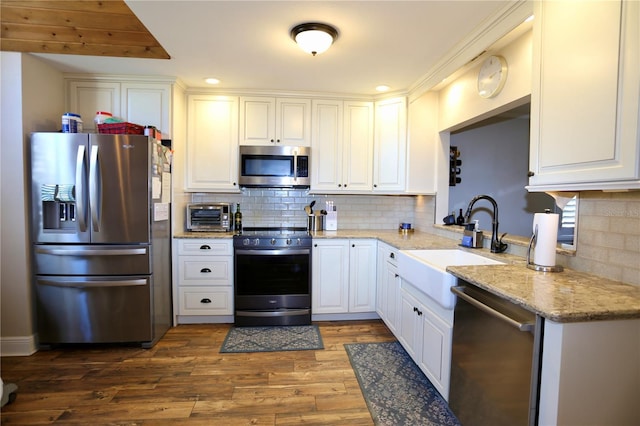 kitchen with sink, dark wood-type flooring, appliances with stainless steel finishes, light stone counters, and white cabinets