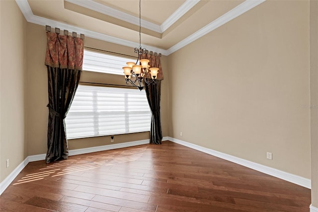 spare room featuring crown molding, a notable chandelier, a tray ceiling, and hardwood / wood-style flooring