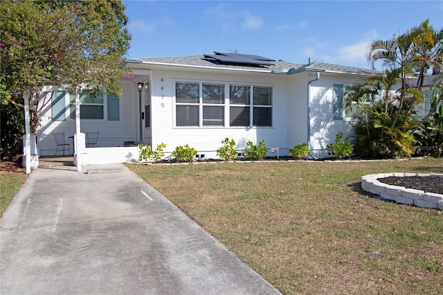 bungalow-style house with solar panels and a front lawn