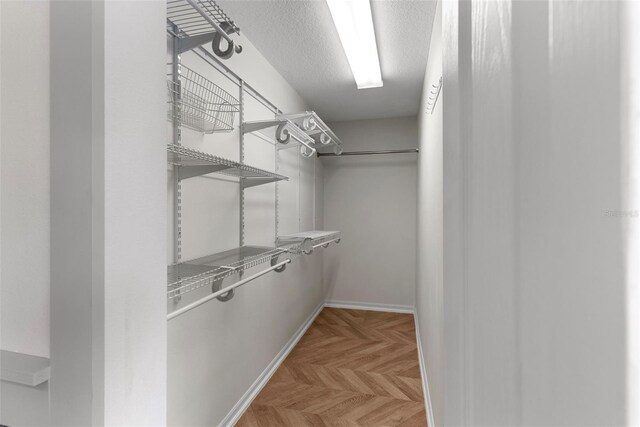 walk in closet with parquet flooring