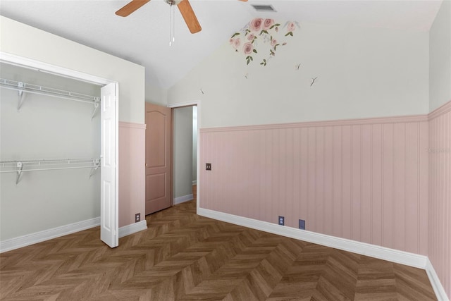 unfurnished bedroom featuring lofted ceiling, dark parquet floors, a closet, and ceiling fan