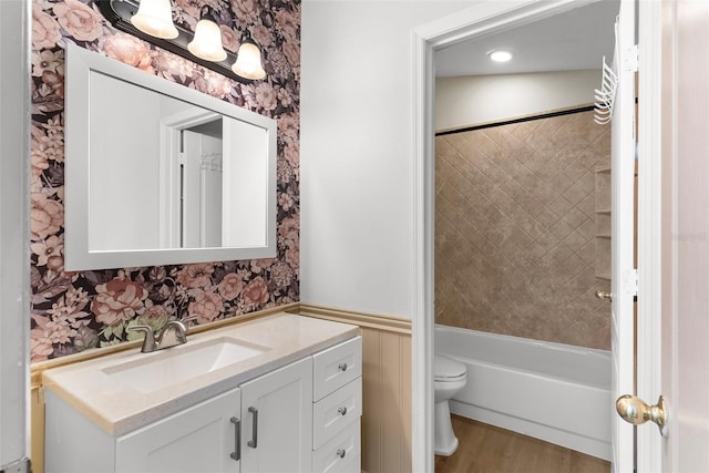 full bathroom featuring vanity, wood-type flooring, tiled shower / bath, and toilet