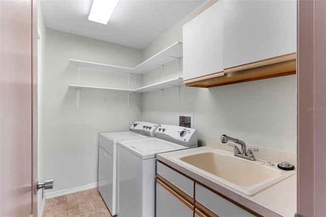 laundry area with cabinets, washing machine and clothes dryer, sink, and a textured ceiling