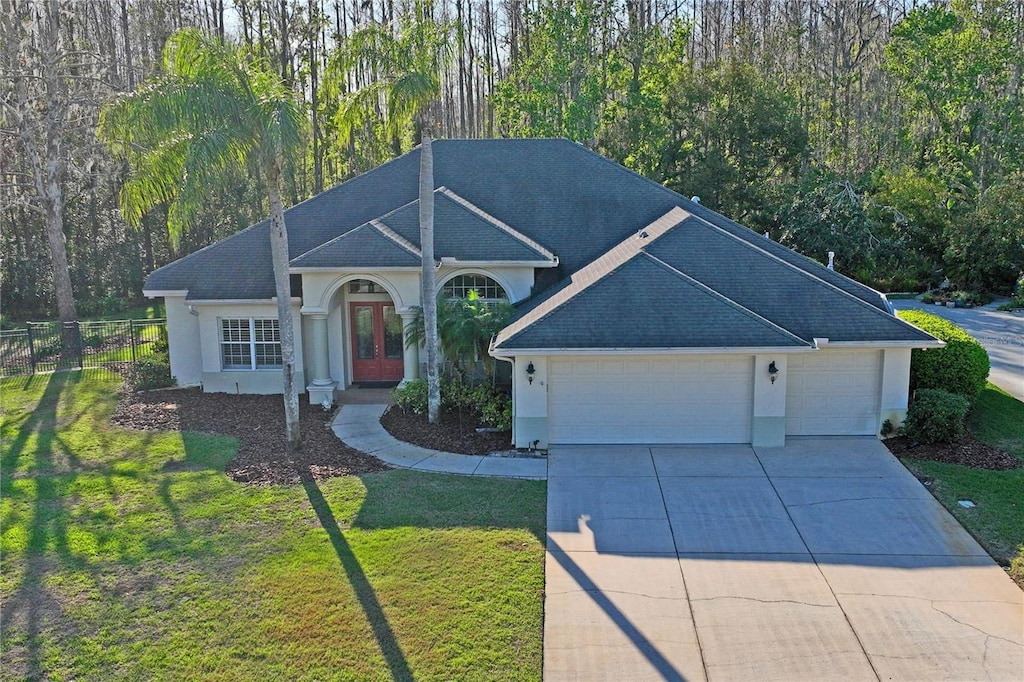 ranch-style home featuring driveway, a front yard, french doors, stucco siding, and an attached garage