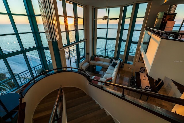 stairs with a water view, a wall of windows, and ceiling fan