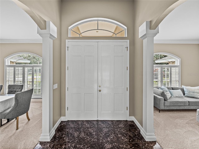 foyer featuring dark carpet and decorative columns