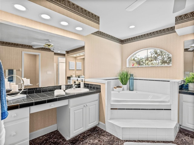 bathroom with vanity, tiled bath, and ceiling fan