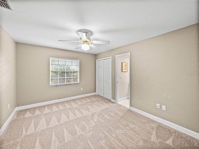 unfurnished bedroom featuring ceiling fan, a closet, and light carpet