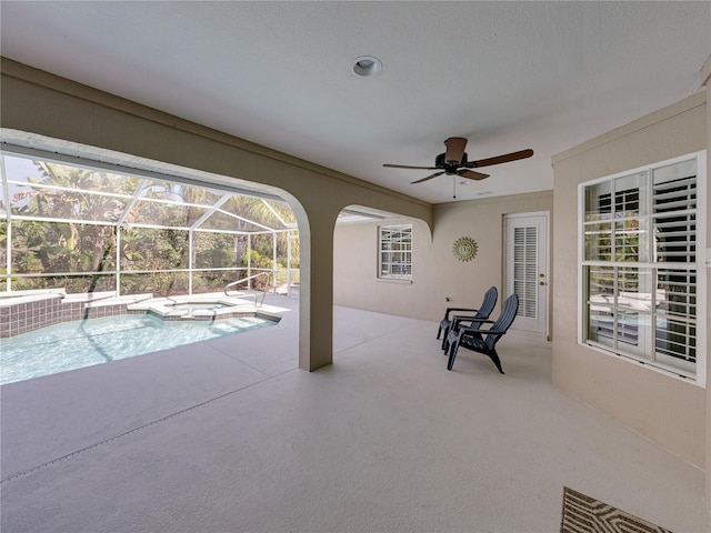 view of swimming pool with an in ground hot tub, ceiling fan, a patio area, and glass enclosure