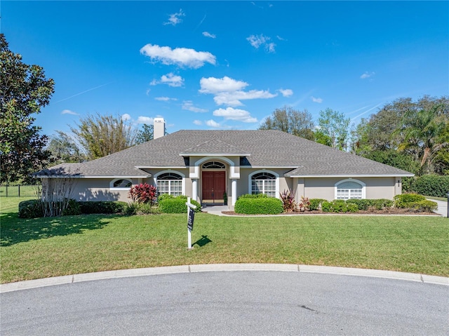 ranch-style house with roof with shingles, a front lawn, a chimney, and stucco siding