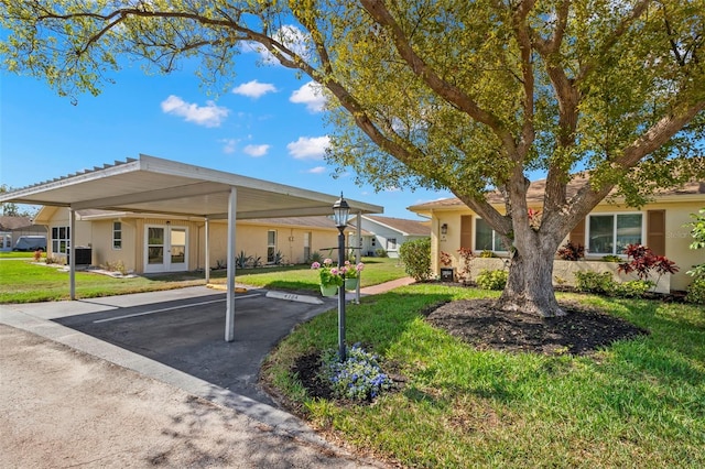 ranch-style home featuring stucco siding, uncovered parking, cooling unit, and a front yard