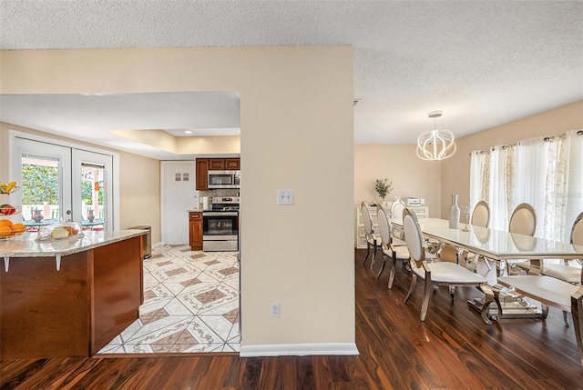 kitchen with dark hardwood / wood-style floors, decorative light fixtures, a chandelier, stainless steel appliances, and french doors