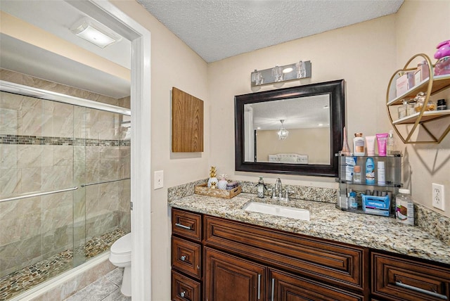 bathroom with toilet, a shower with shower door, a textured ceiling, vanity, and tile patterned flooring