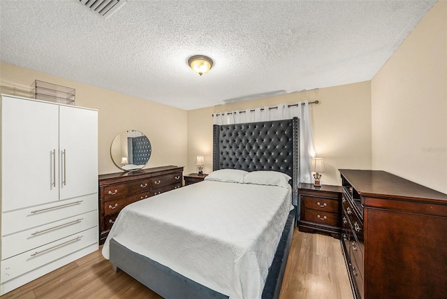 bedroom featuring a textured ceiling and light hardwood / wood-style flooring