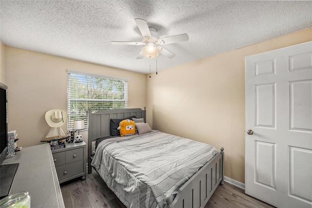 bedroom featuring ceiling fan, dark hardwood / wood-style floors, and a textured ceiling