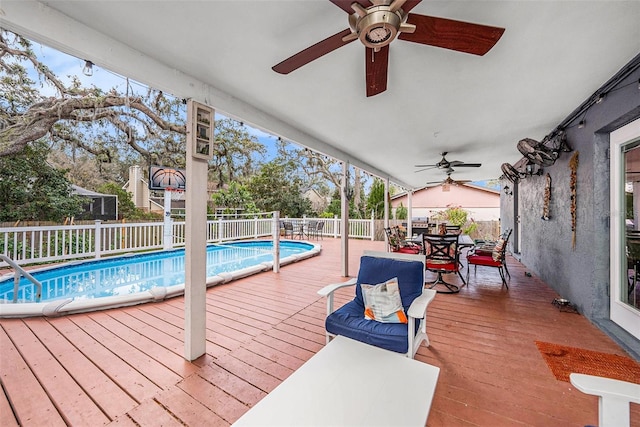 deck with ceiling fan and a fenced in pool