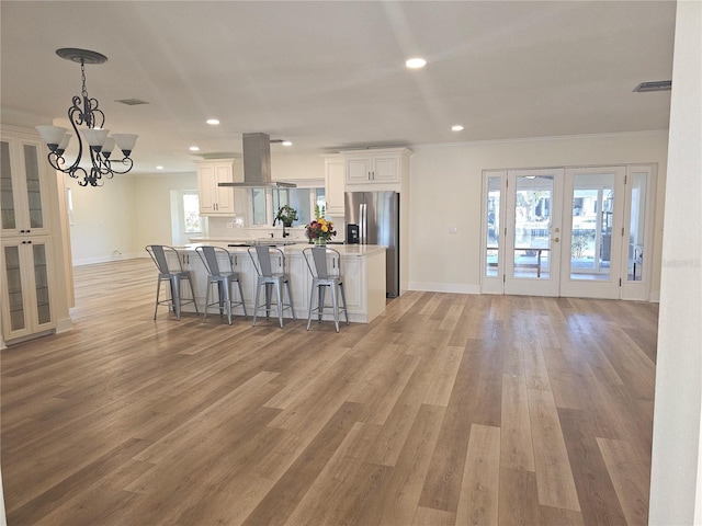 kitchen with a kitchen breakfast bar, light countertops, french doors, white cabinetry, and stainless steel refrigerator with ice dispenser