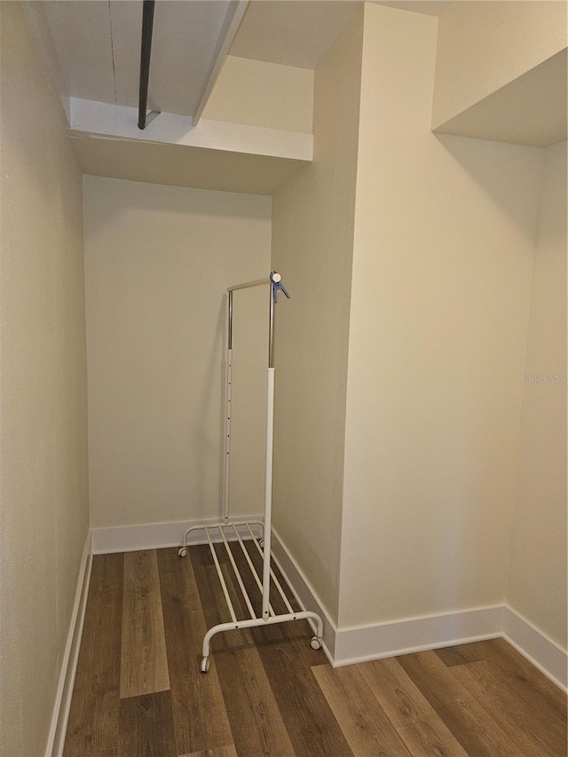 clothes washing area with baseboards and wood finished floors