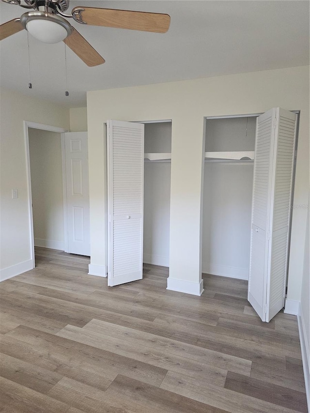 unfurnished bedroom featuring light wood finished floors, baseboards, and multiple closets